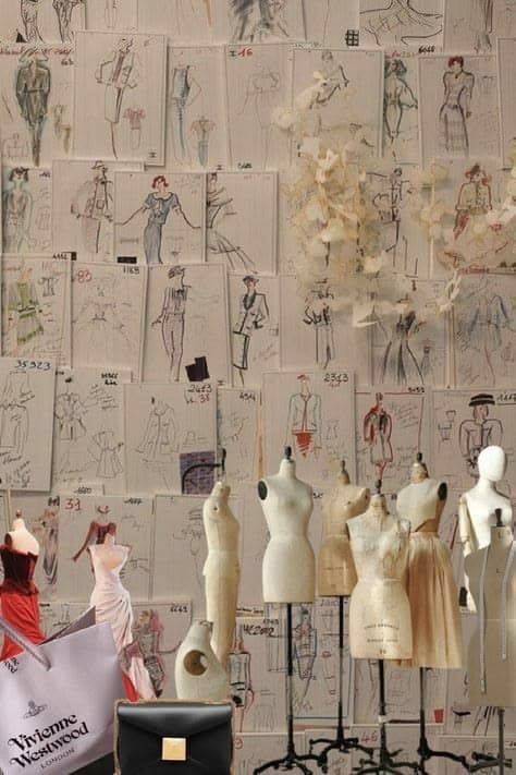 A wall of fashion sketches behind a row of dress forms